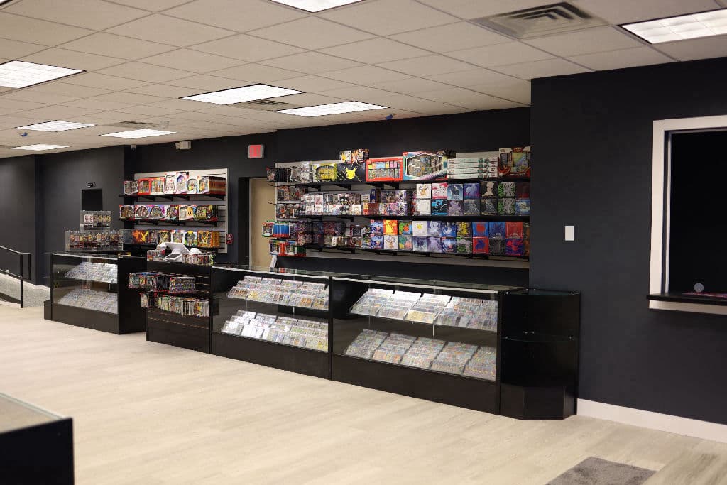 Inside The Card Collective NY: wall of sealed Pokemon and TCG product above glass cases full of graded and raw singles
