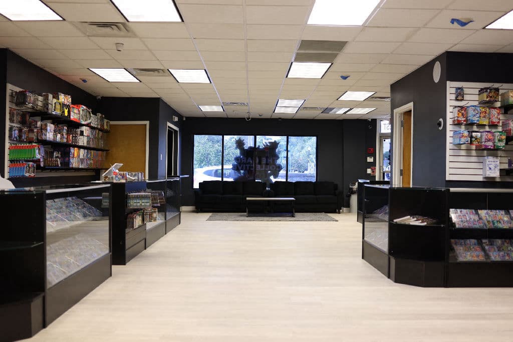 The Card Collective NY main floor looking toward the front window, with display cases either side and a lounge area for play